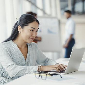 A professional woman logs into her Patelco Online account on her laptop at work.